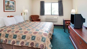 A hotel room with a large bed, a chair, a television, and a window with curtains.