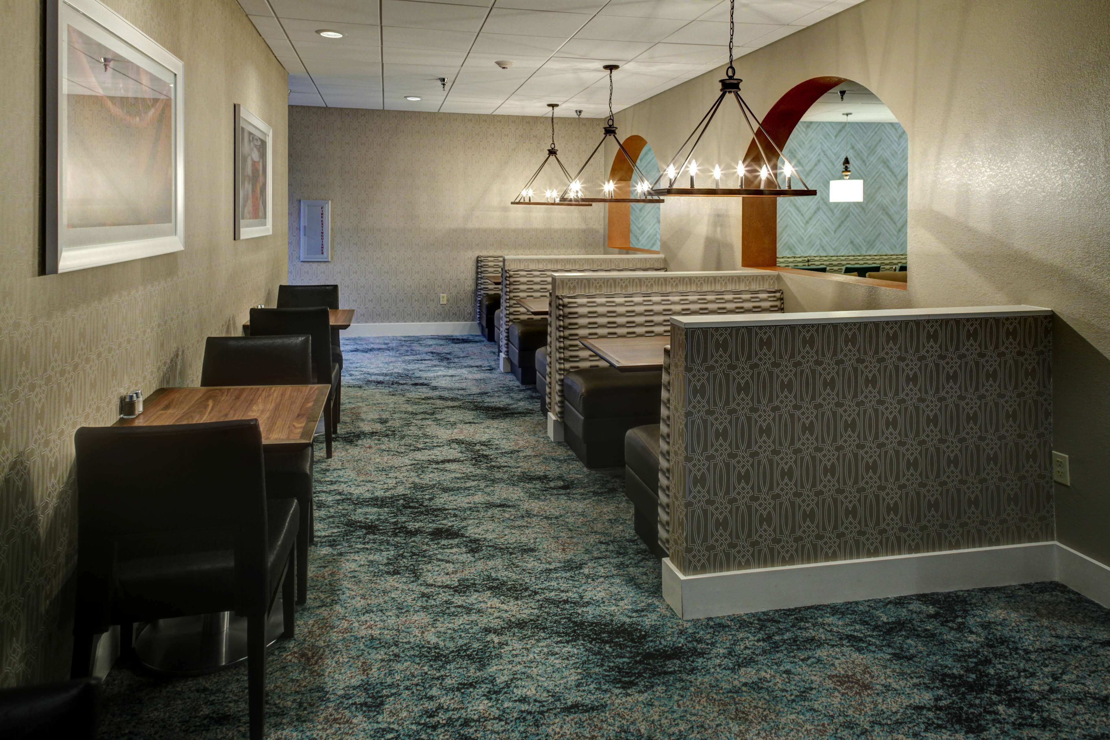 A hotel lobby with a carpeted floor, seating areas, and a chandelier.