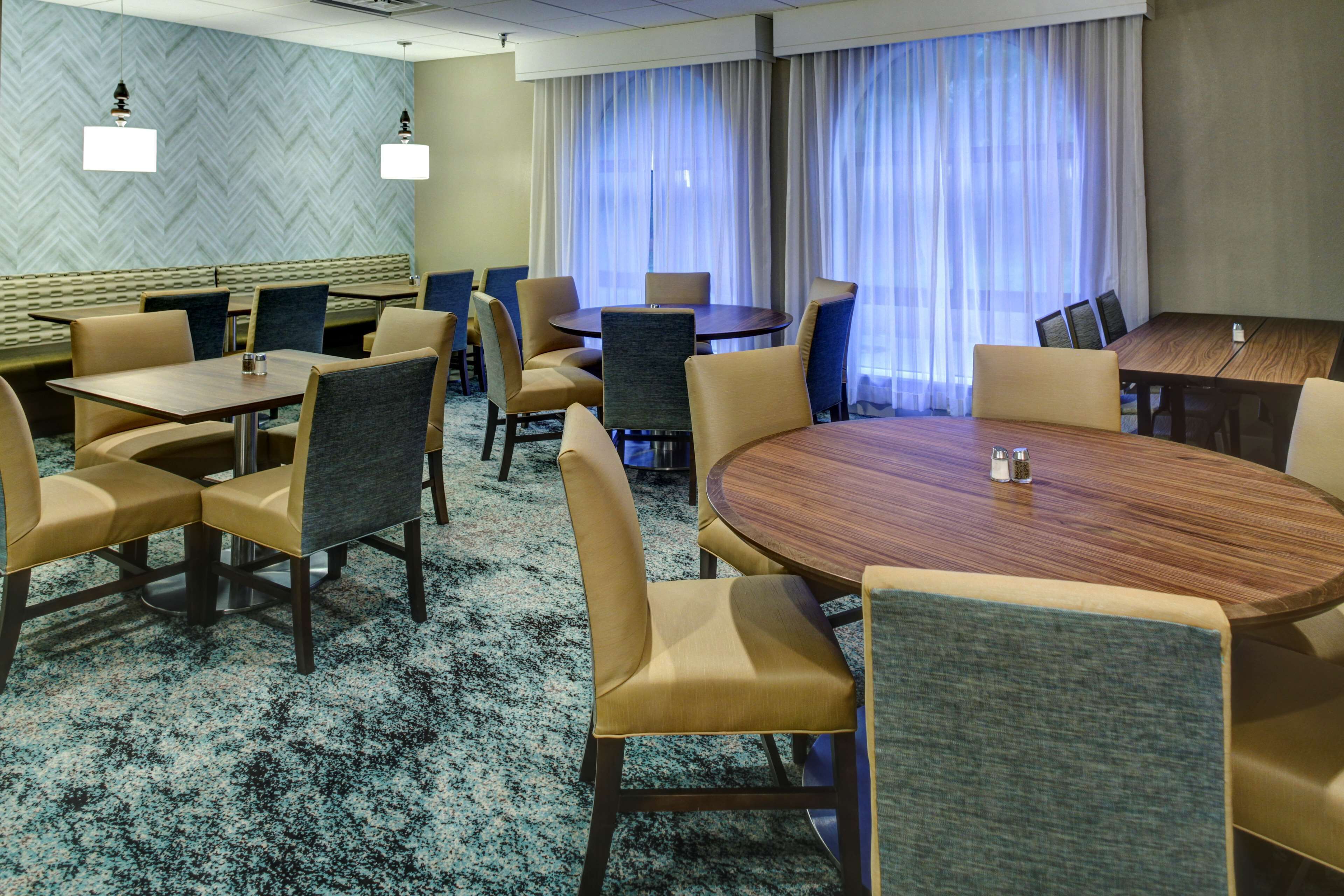 A hotel conference room with a large round table, several smaller tables, and comfortable seating.