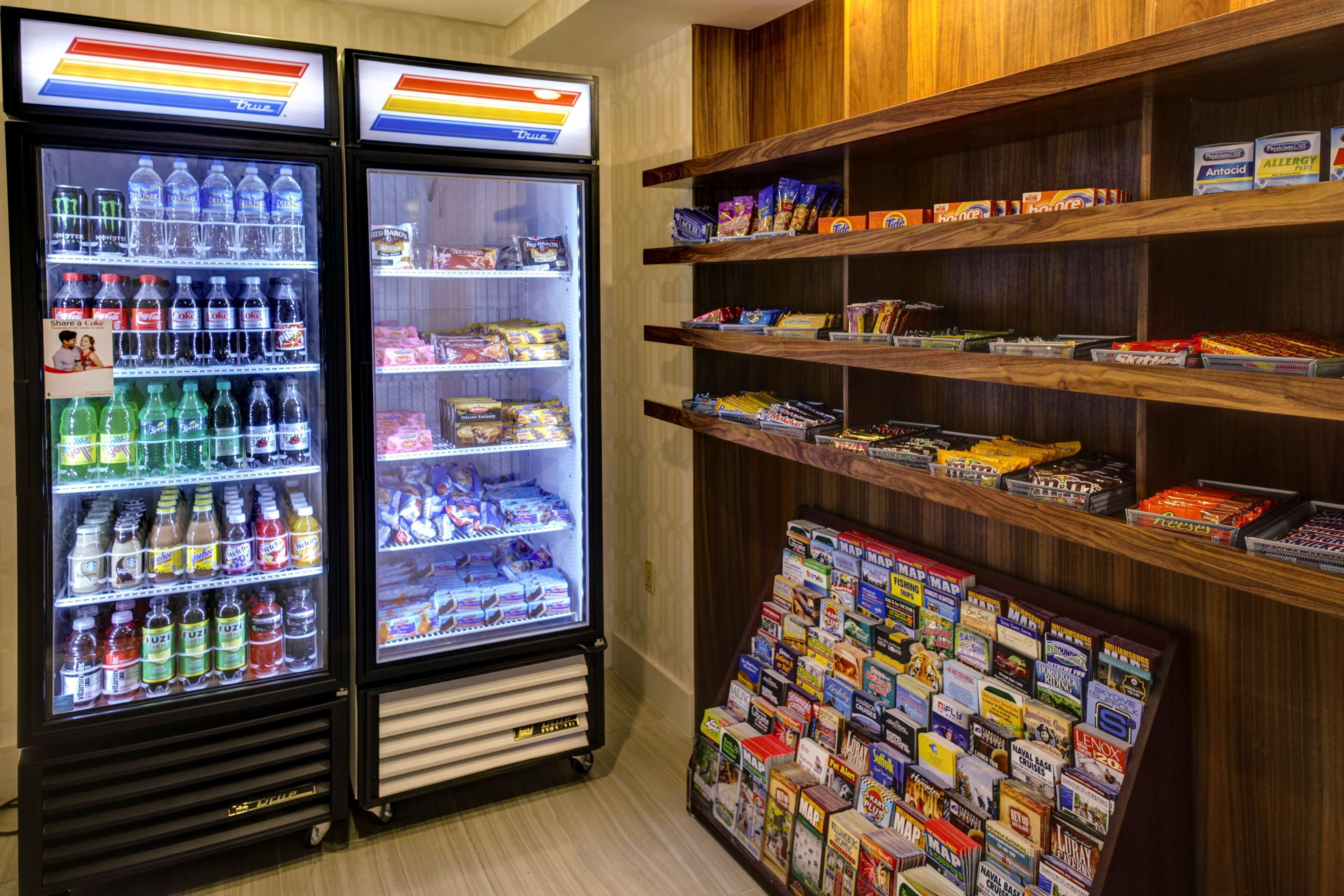Un espace de vente proposant deux distributeurs automatiques de boissons réfrigérées, ainsi que des étagères remplies d’en-cas et de magazines.