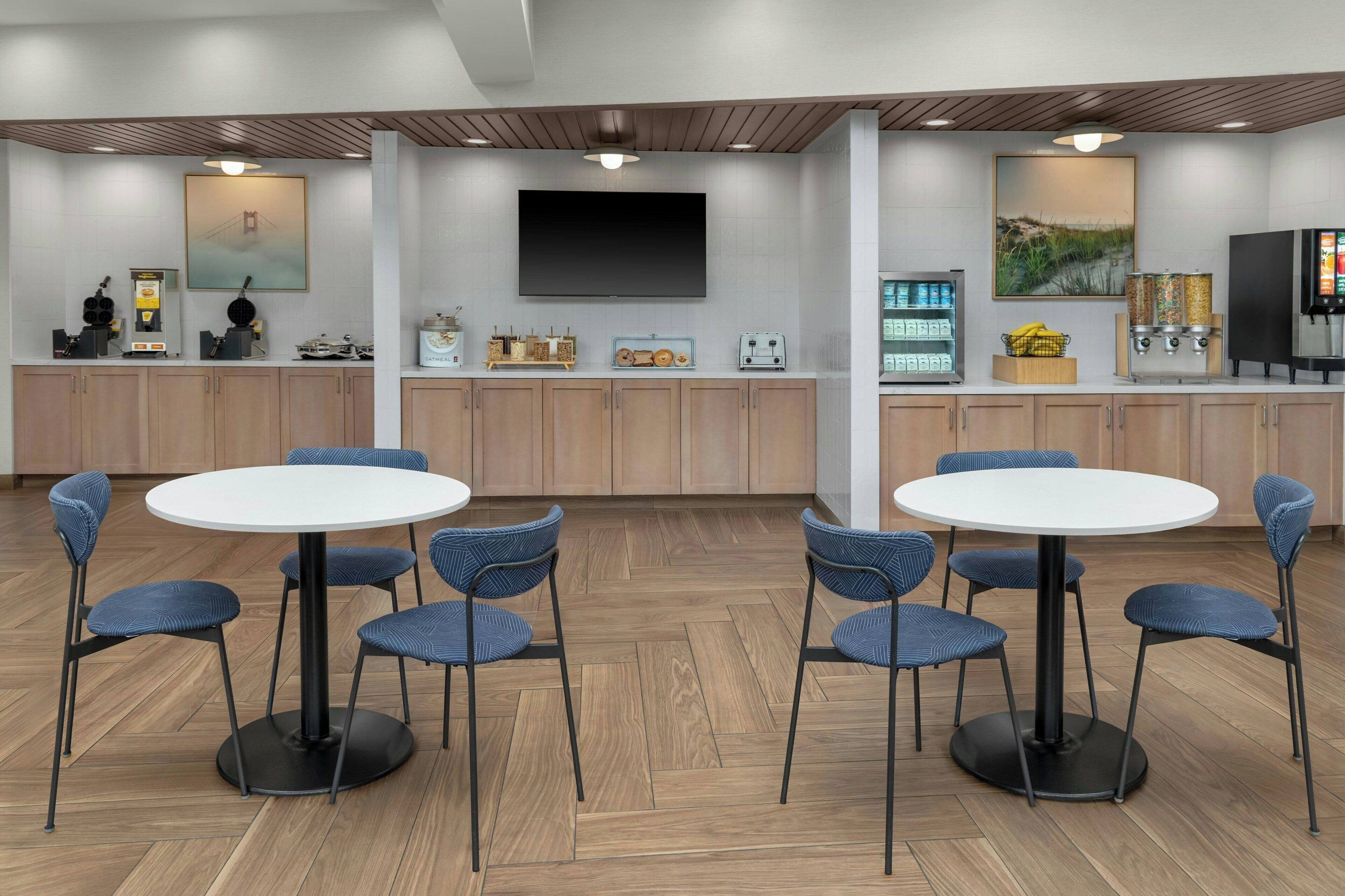 Un'area cucina moderna con una TV a schermo piatto, una macchina del caffè e un frigorifero.