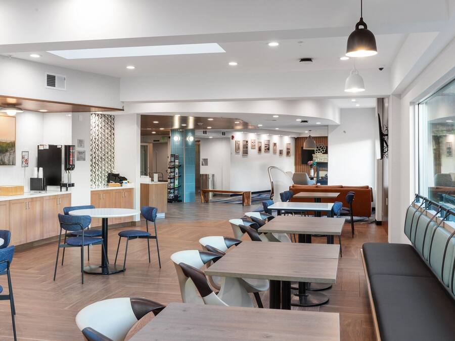 Een moderne eetruimte met houten tafels en stoelen, een bar en een zithoek met uitzicht.