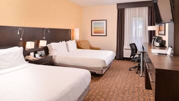A hotel room with two beds, a desk, a chair, a telephone, and a painting on the wall.