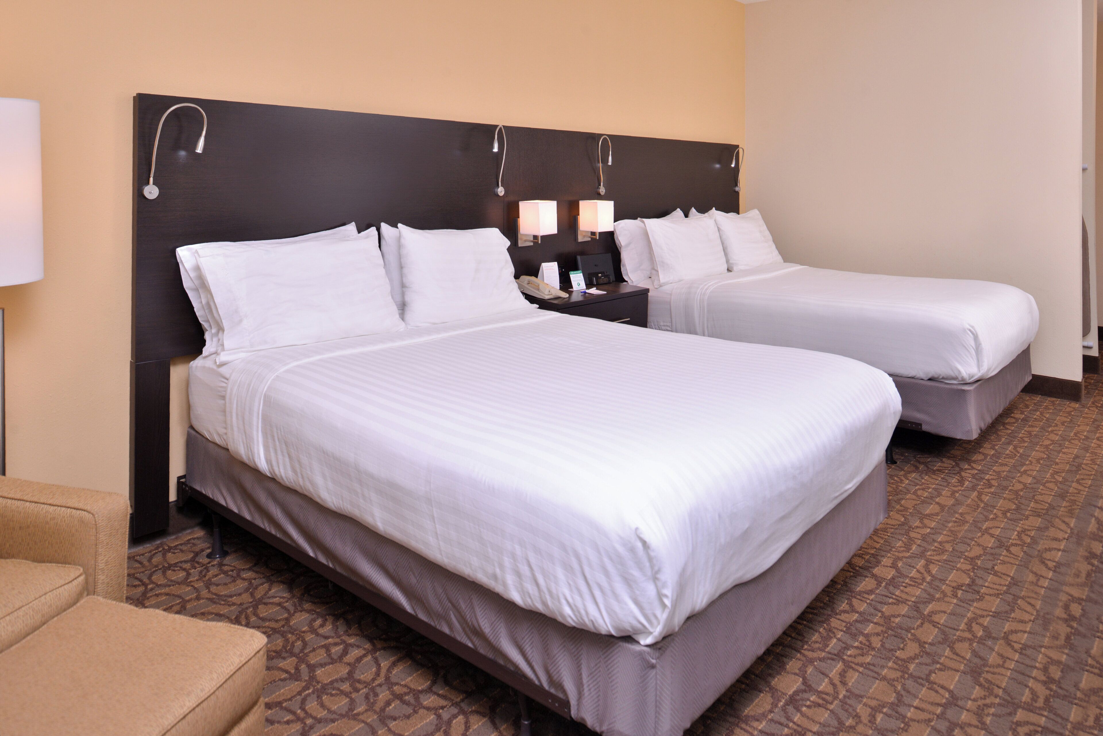 A hotel room with two beds, a nightstand with lamps, and a patterned carpet.