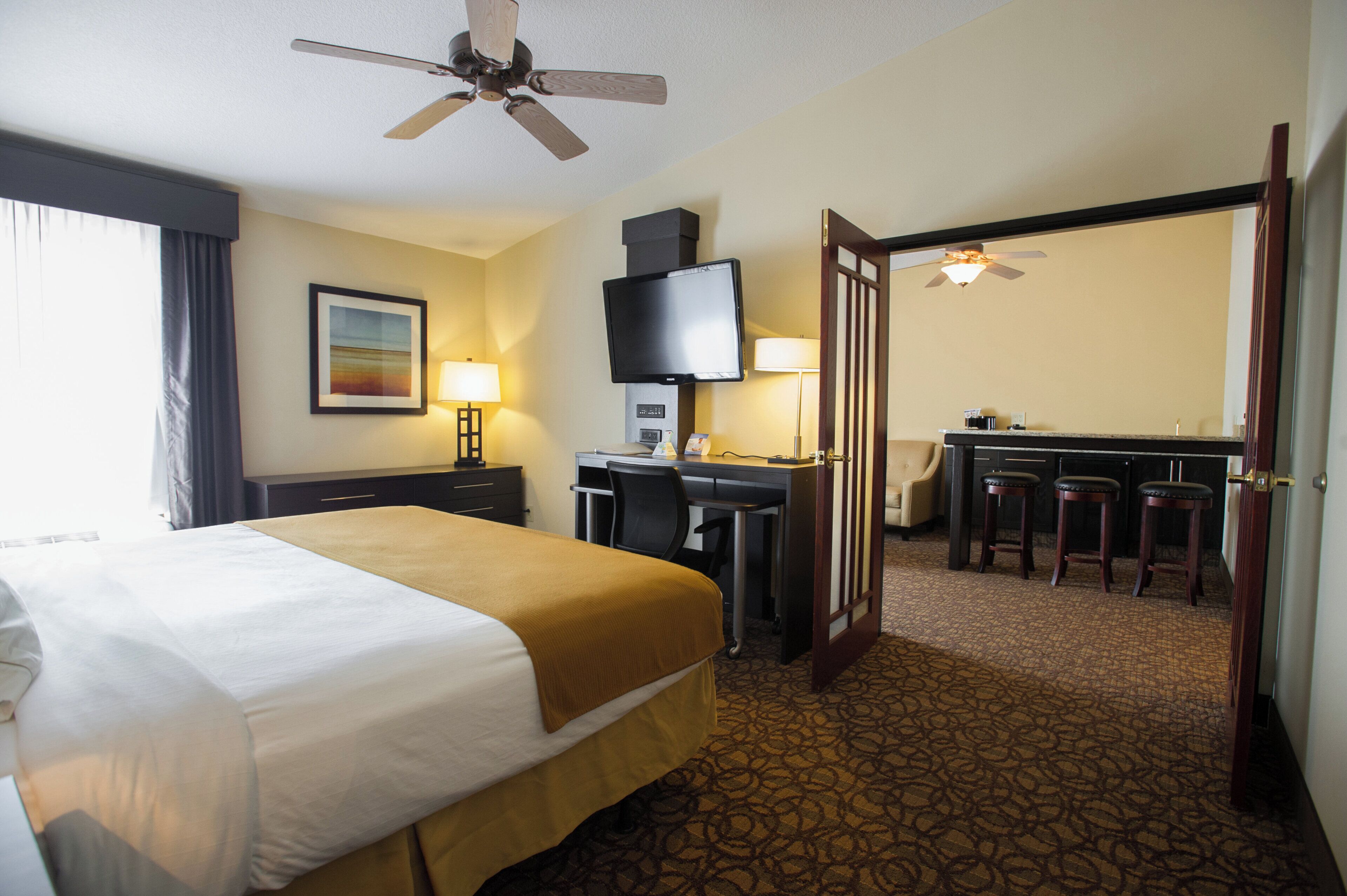 A hotel room with a bed, desk, chair, television, and a door leading to a bathroom.