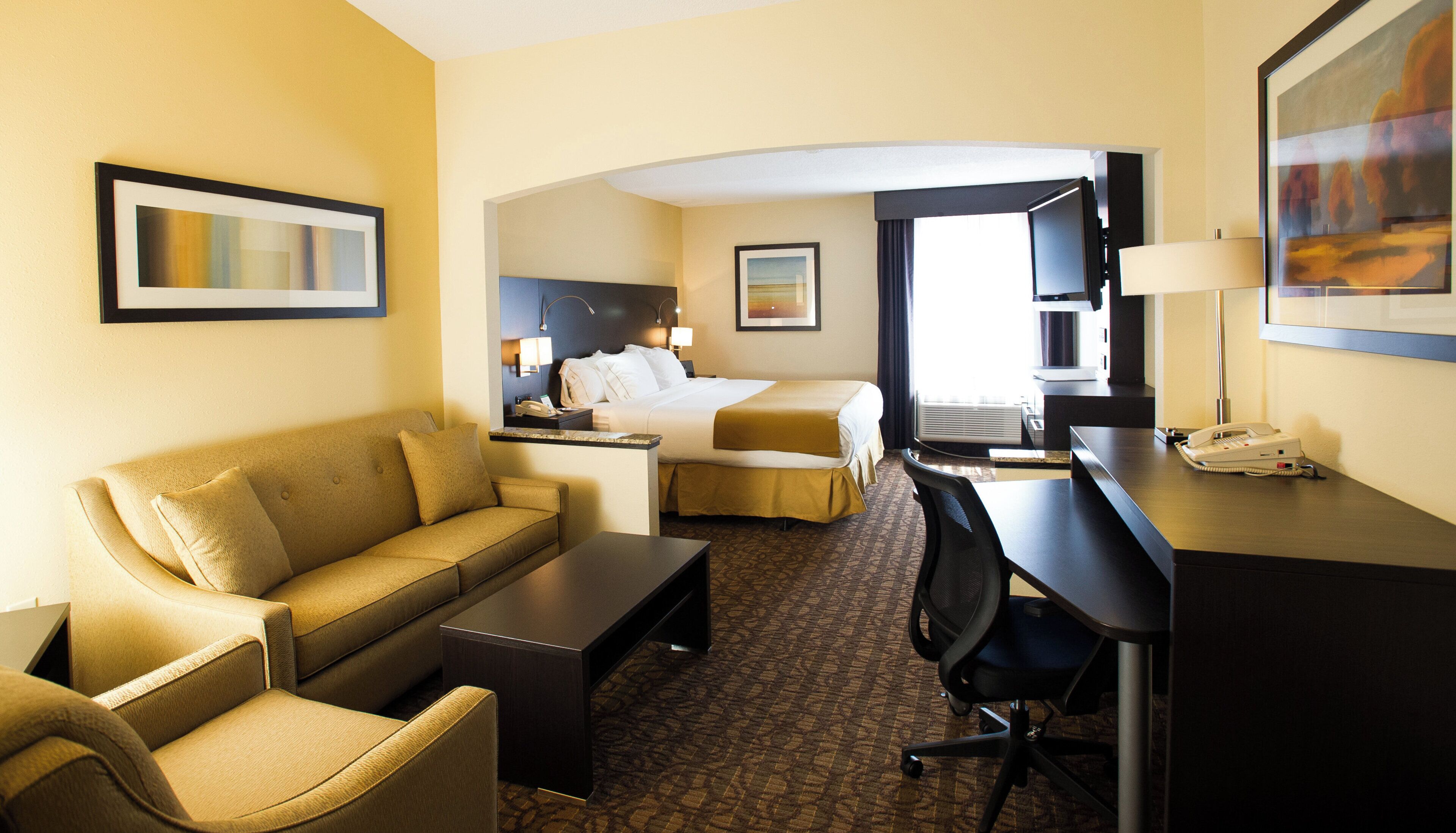 Une chambre d’hôtel équipée d’un lit, d’un bureau, d’une chaise, d’un canapé et d’une machine à café.