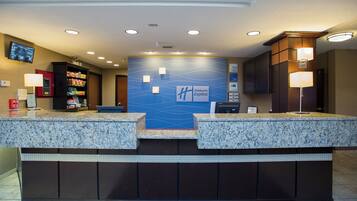 A hotel reception area with granite counters, a blue wall with the Holiday Inn Express logo, and a security camera on the ceiling.