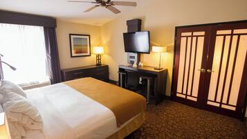 A hotel room with a bed, a desk, a television, and a door.