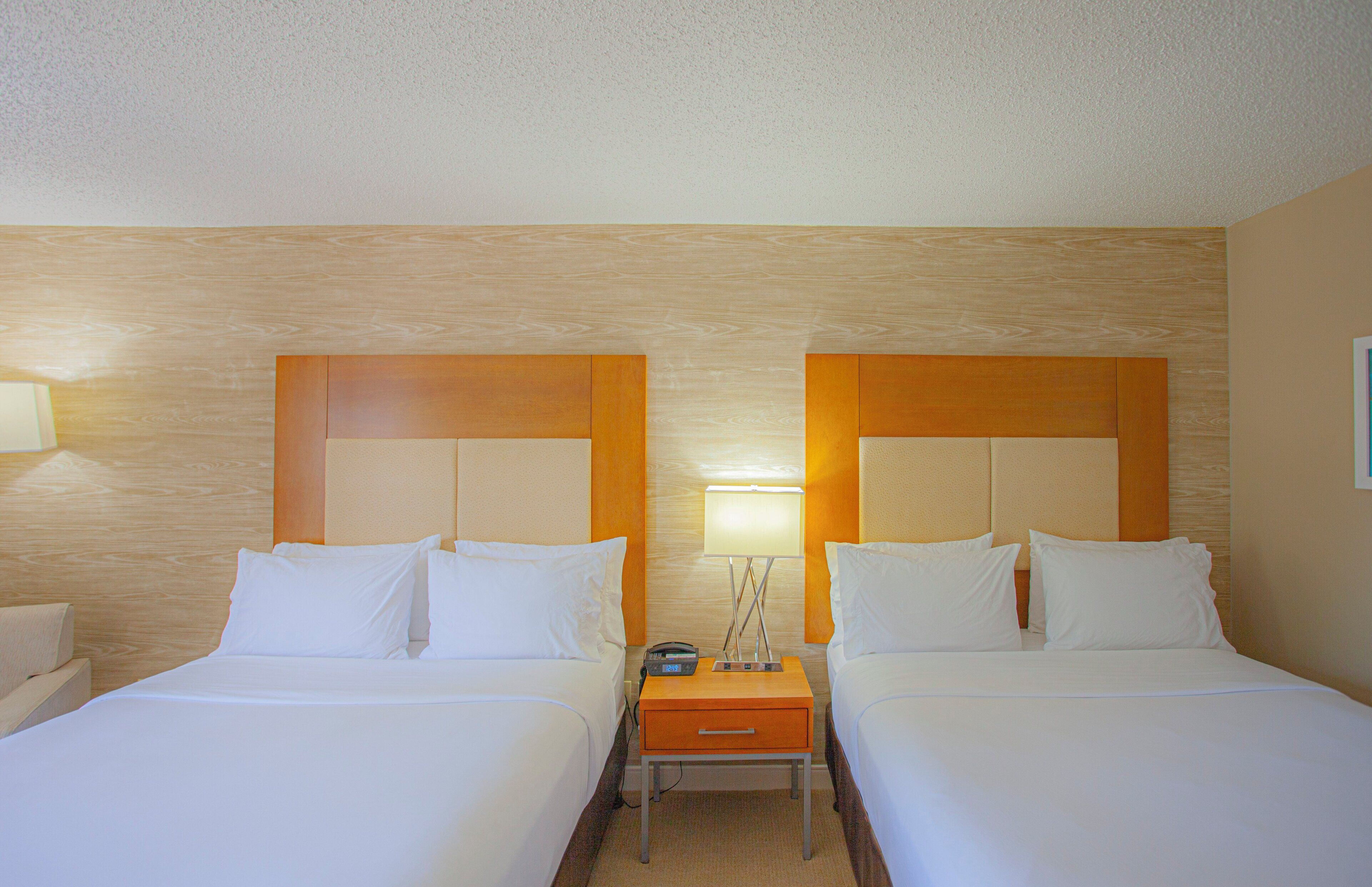 Habitación de hotel con dos camas, una mesita de noche y una lámpara.