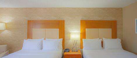Habitación de hotel con dos camas, una mesita de noche y una lámpara.