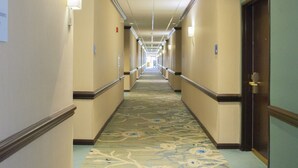 A hotel hallway with carpeted floors, doors on both sides, and overhead lighting. - Holiday Inn & Suites Spring- The Woodlands Area by IHG (Spring)