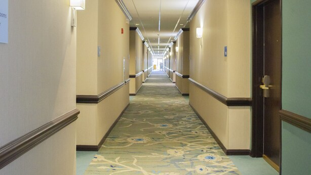 A hotel hallway with carpeted floors, doors on both sides, and overhead lighting. - Holiday Inn & Suites Spring- The Woodlands Area by IHG (Spring)