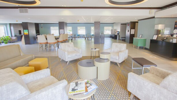 A spacious lobby with multiple seating areas, including sofas and chairs, a reception desk, and a coffee station. - Holiday Inn & Suites Spring- The Woodlands Area by IHG (Spring)