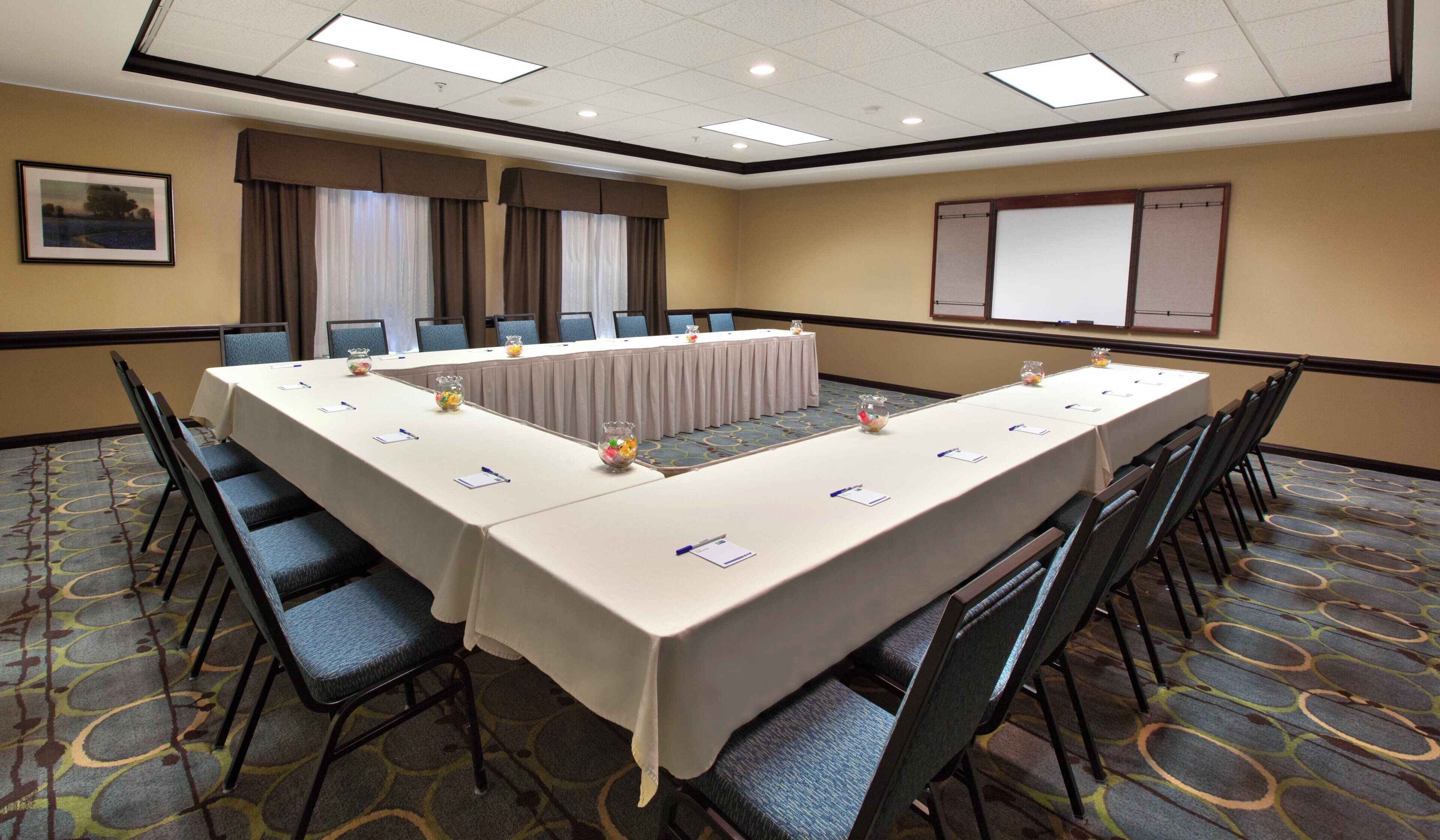 A conference room with a long table, chairs, and a projector screen.