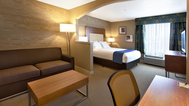 A hotel room with a sofa, a bed, a desk, and a chair. - Holiday Inn & Suites Spring- The Woodlands Area by IHG (Spring)