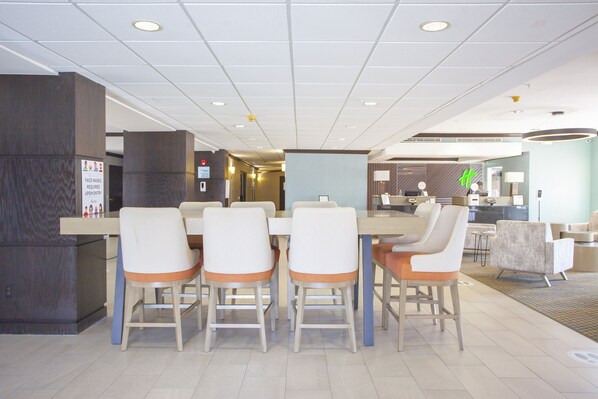 En hotelllobby med en receptionsdisk, en matplats med bord och stolar samt en sittgrupp med soffor.