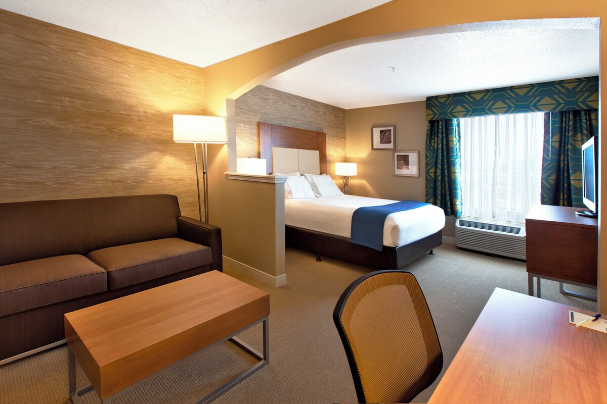 Ett hotellrum med en säng, en soffa, ett skrivbord, en stol och en lampa.