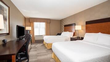 A hotel room with two beds, a desk with a TV, and a chair.