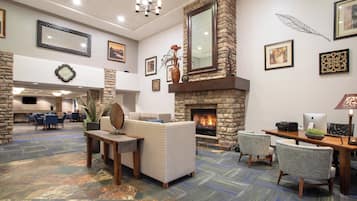 Eine Lobby mit Kamin aus Stein, Sitzgelegenheiten und einer großen Wanduhr.
