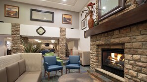 A lobby with a stone fireplace, seating area, and framed artwork on the walls.