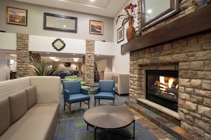 A lobby with a stone fireplace, seating area, and framed artwork on the walls. - Holiday Inn Express & Suites Denver SW-Littleton by IHG (Littleton)