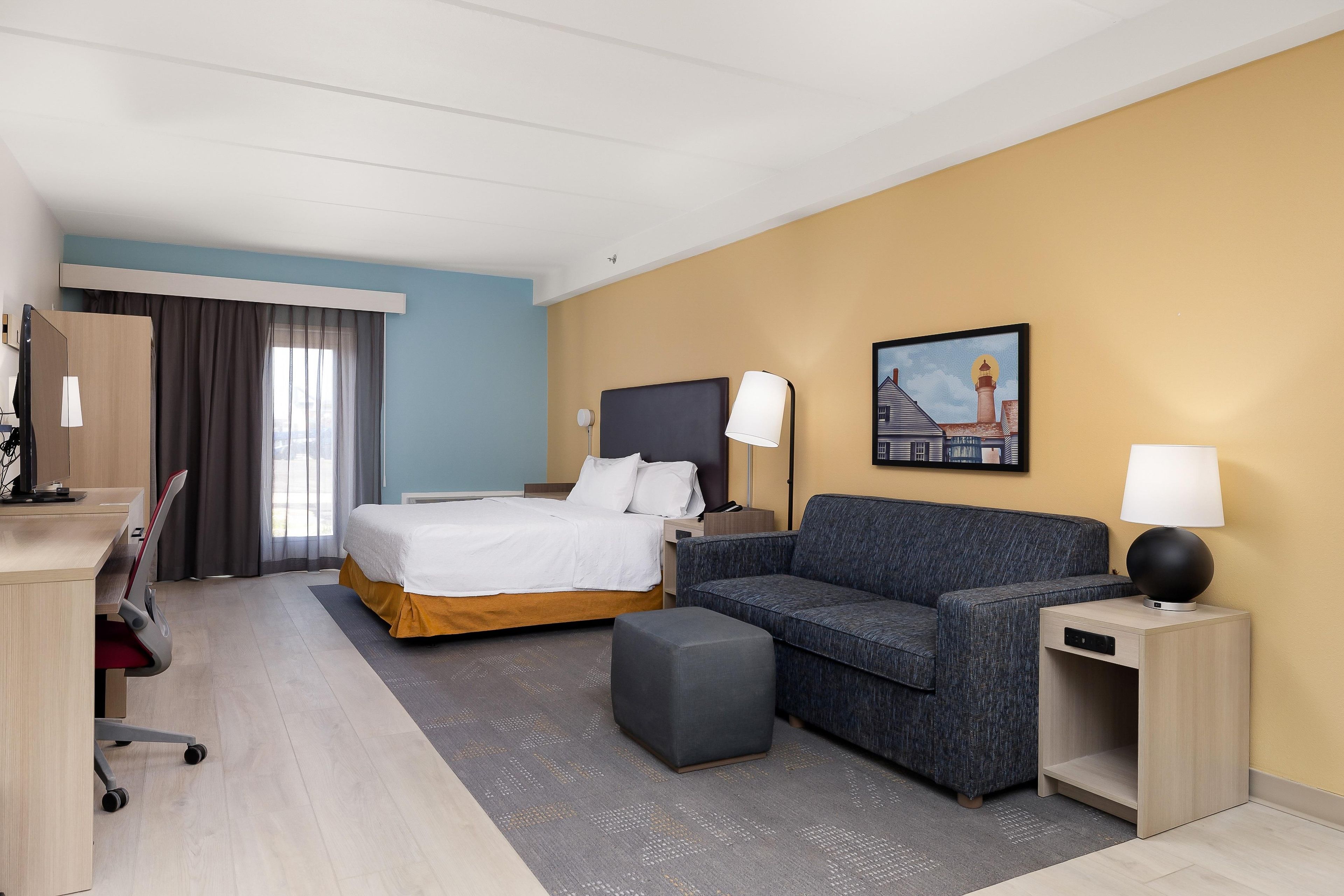 A hotel room with a bed, a sofa, a desk, and a chair.