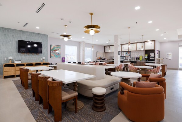 A modern dining area with tables and chairs, a flat-screen TV, and artwork on the walls.
