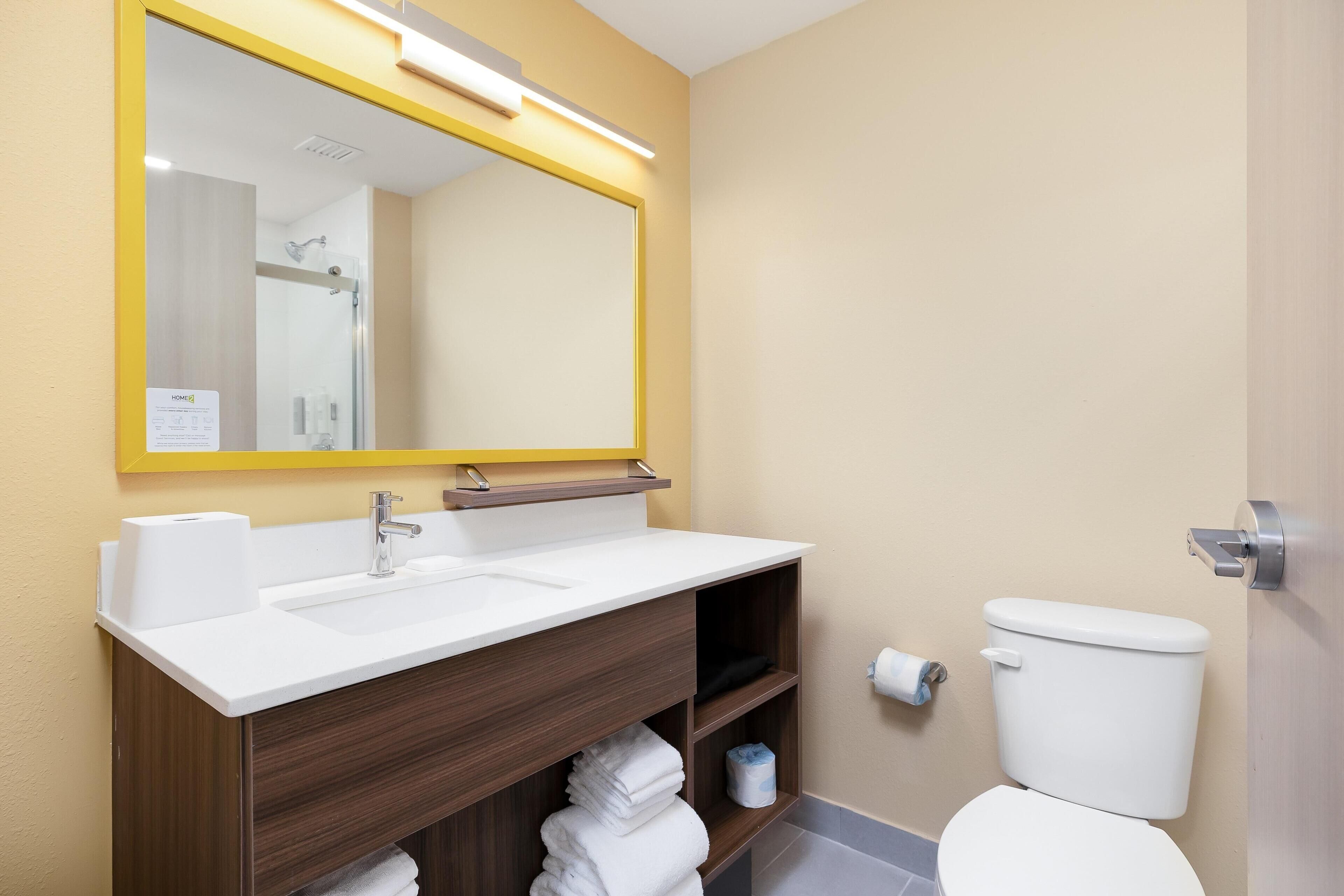 A bathroom with a white sink, mirror, and toilet.