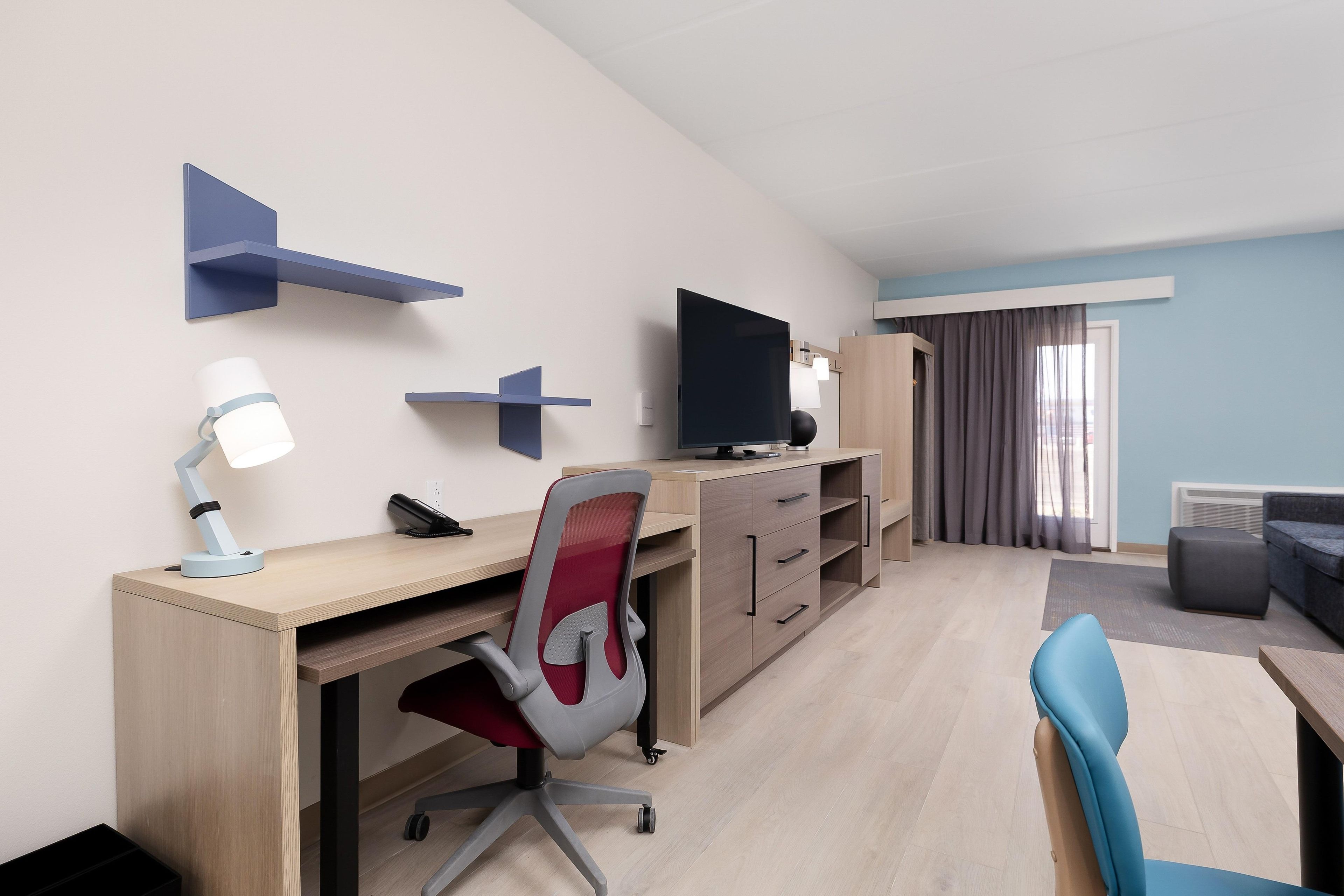 Una habitación de hotel con escritorio, silla, televisor y sofá.