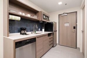 A compact kitchen with a dishwasher, a coffee maker, and a microwave.