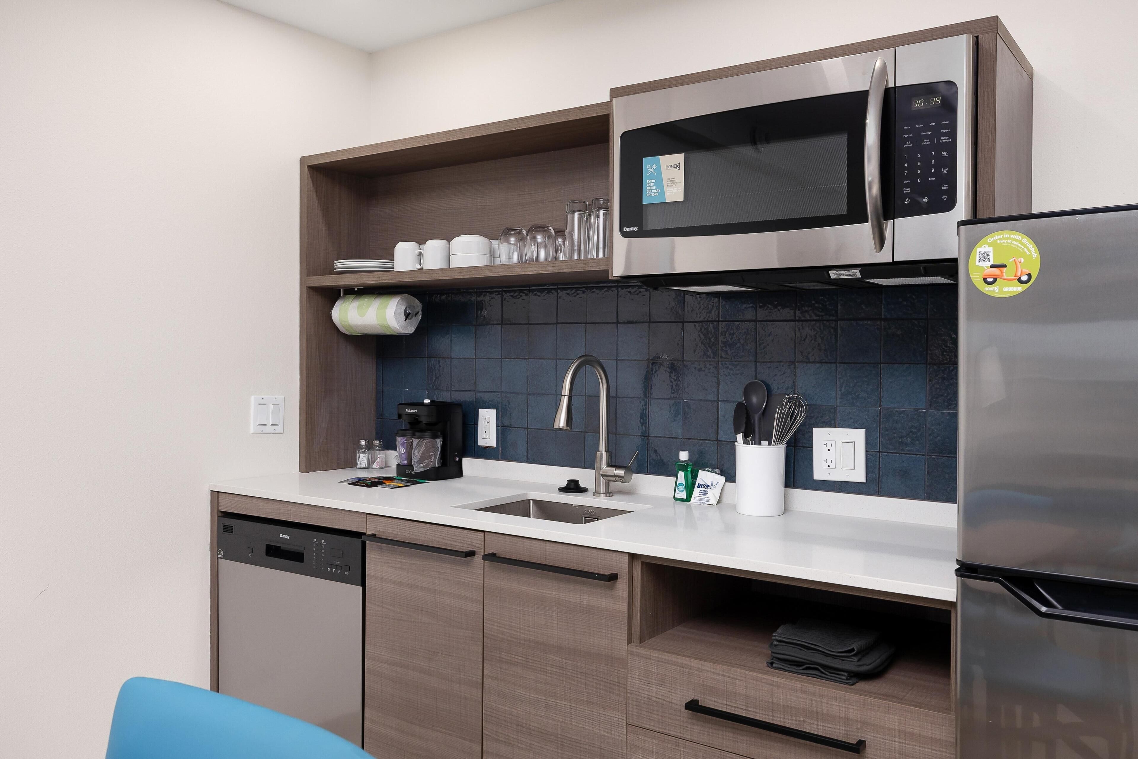 A modern kitchen with a dishwasher, microwave, refrigerator, and a sink.