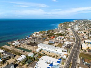 Vista aérea de una ciudad costera con una carretera principal que la atraviesa, un puerto deportivo y varios edificios.