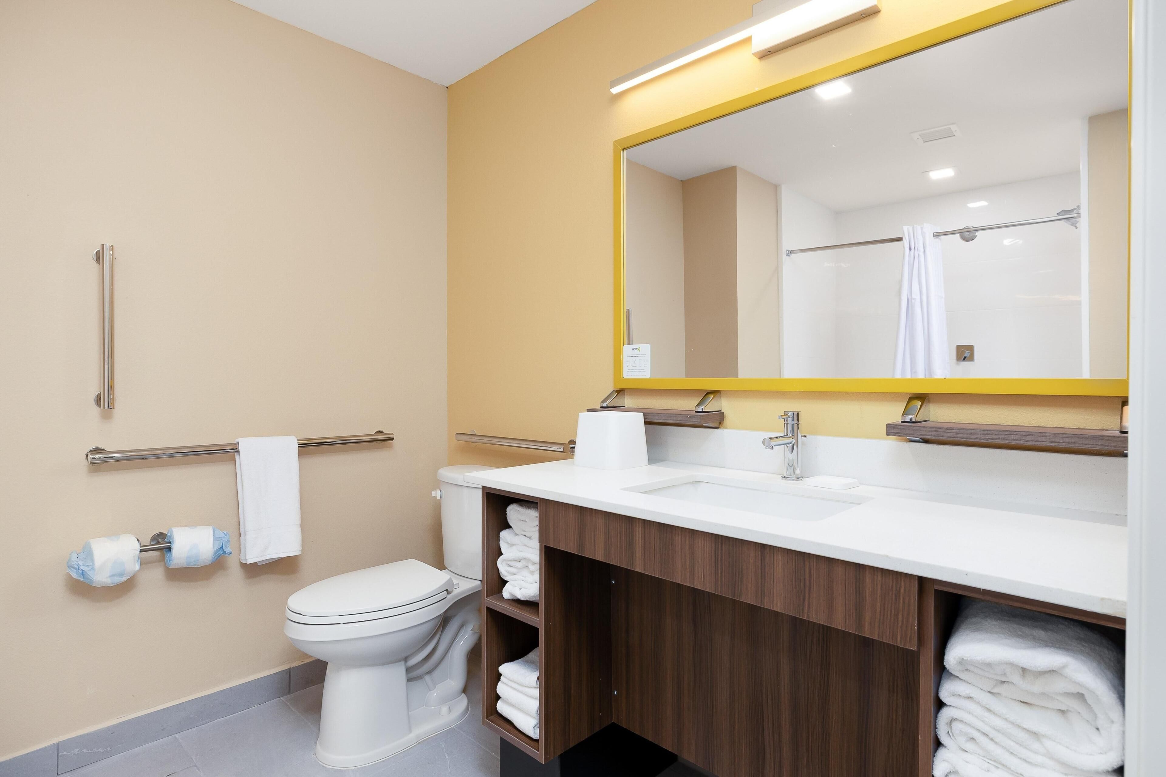 Un baño moderno con inodoro, lavamanos y espejo.