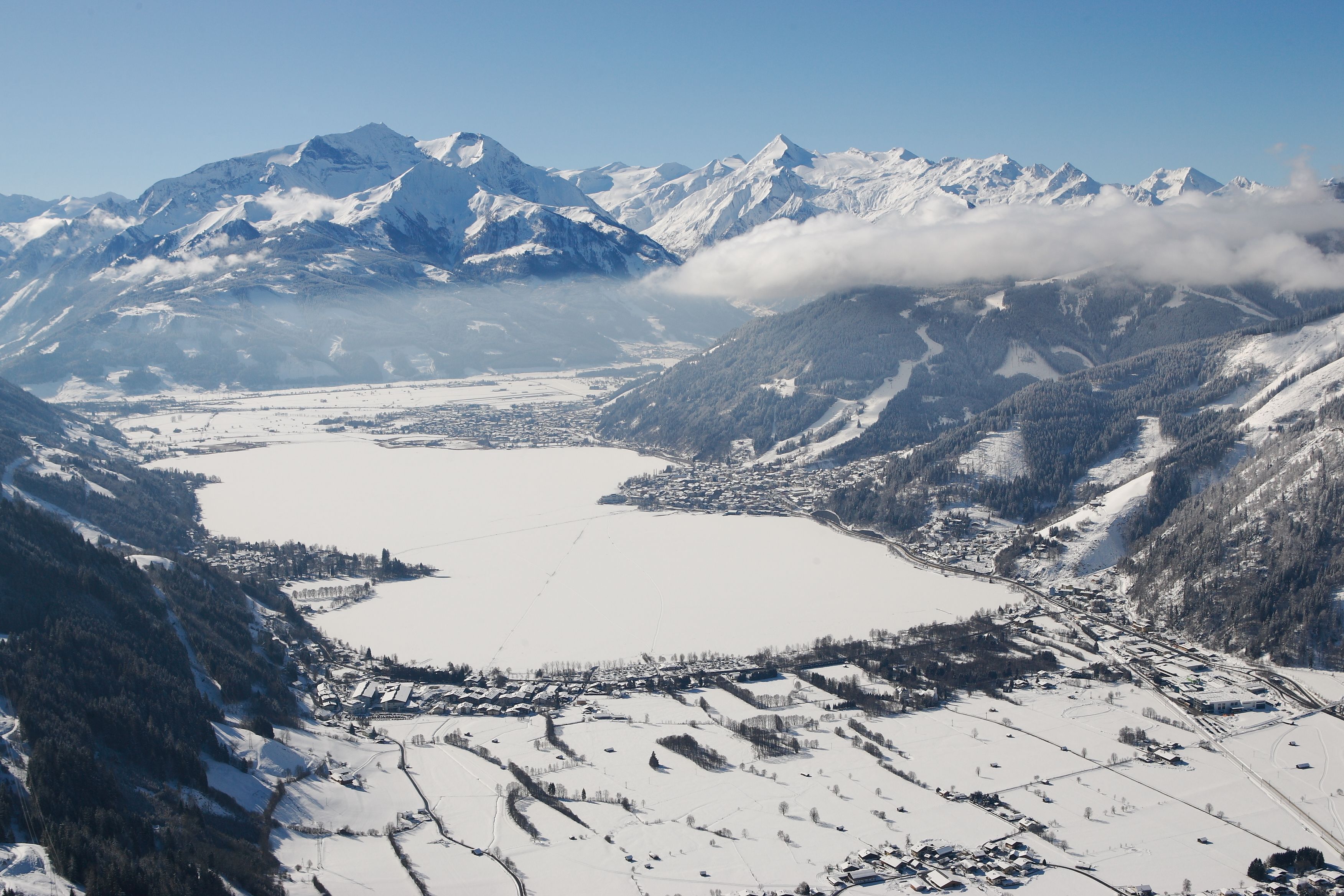 A panoramic view of a snow-covered valley with mountains in the background and a small town in the foreground.