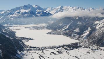 A panoramic view of a snow-covered valley with mountains in the background and a small town in the foreground.