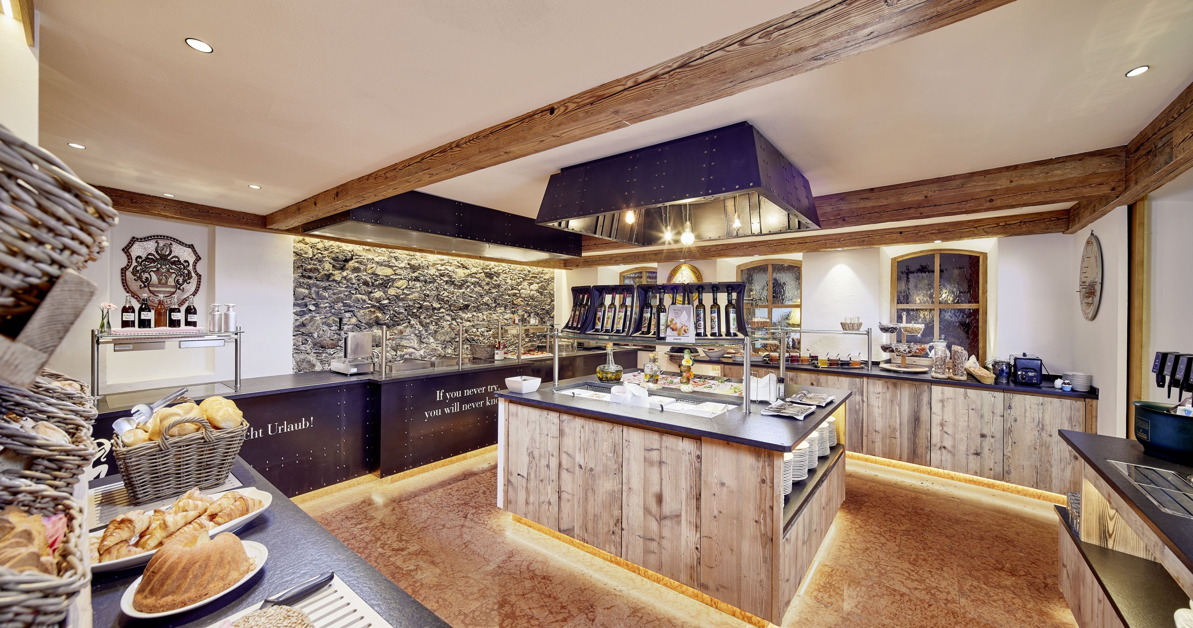 A breakfast bar with a stone wall backdrop, wooden beams, and a variety of breakfast items.
