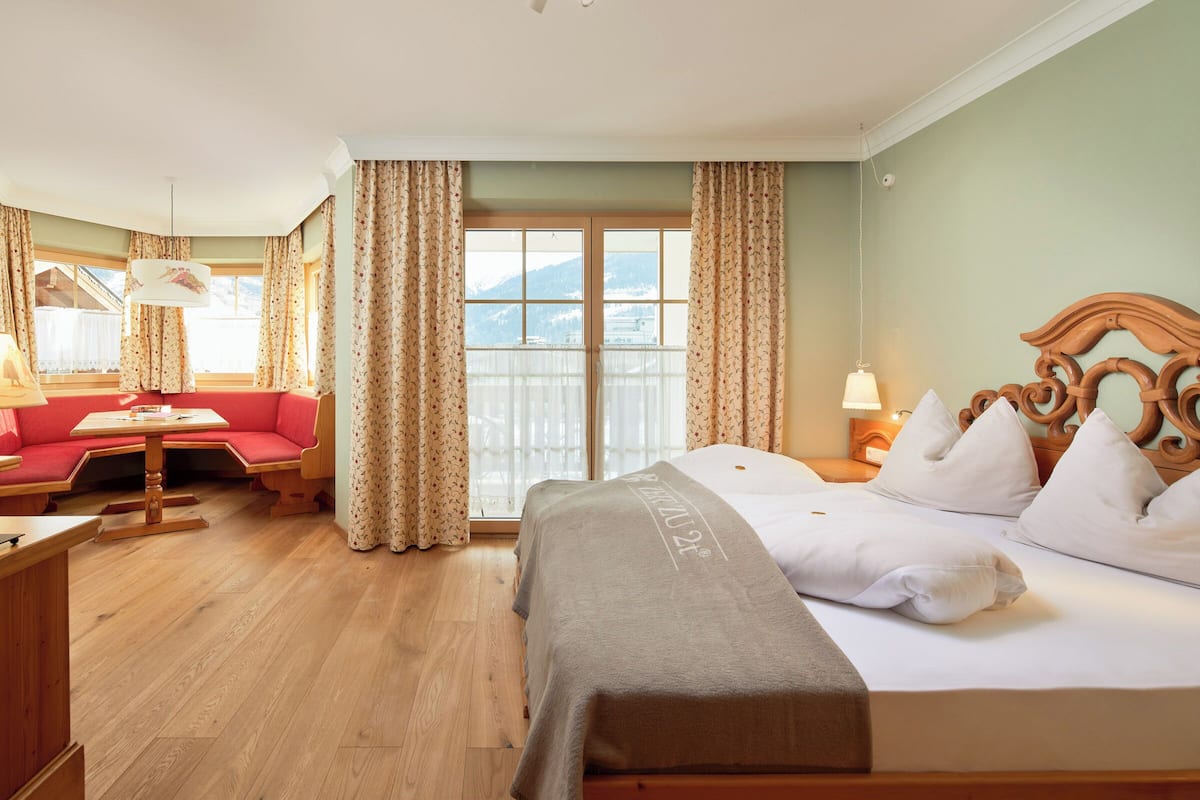 Une chambre d’hôtel avec un lit, un canapé, une table et une fenêtre avec des rideaux.