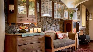 A cozy room with a stone wall, wooden furniture, a vintage guitar, and framed pictures.