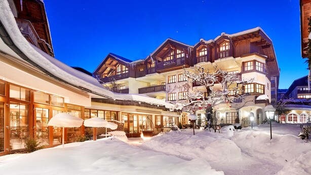 Een gebouw bedekt met sneeuw, met meerdere balkons en grote ramen, waarschijnlijk een hotel of resort.