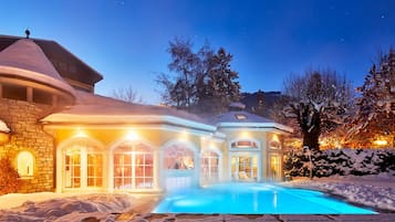 Una piscina techada, una piscina al aire libre, sombrillas