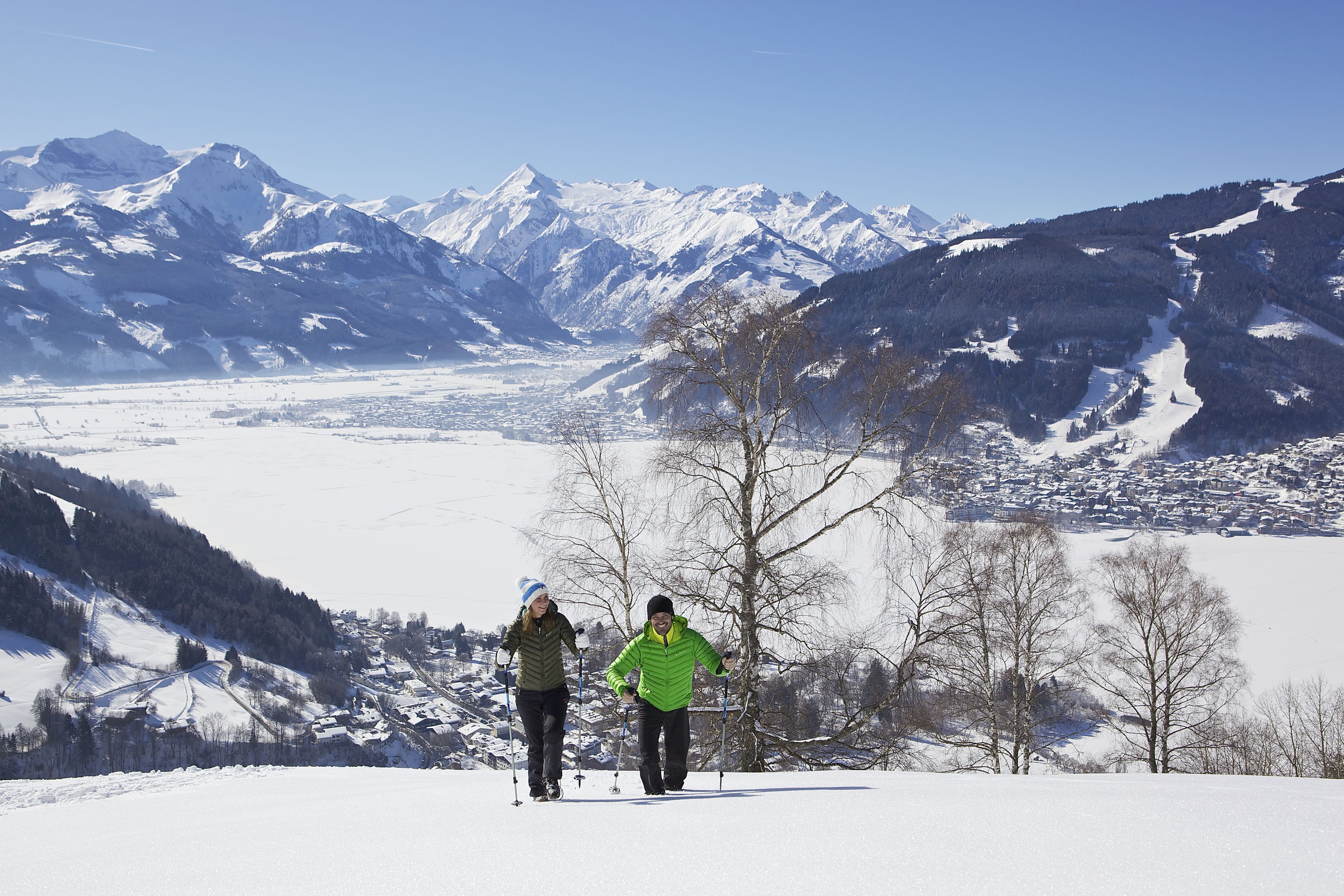 A snowy mountain landscape with two skiers.