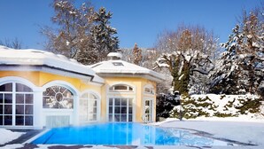 Een huis met een zwembad, omgeven door met sneeuw bedekte bomen.