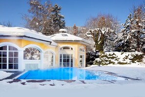 Una piscina cubierta, una piscina al aire libre, sombrillas, tumbonas