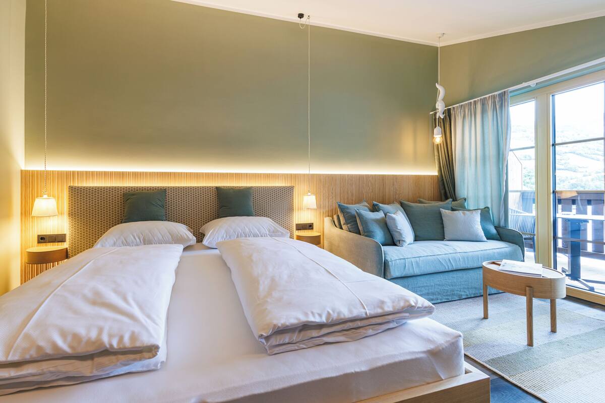 Une chambre d’hôtel avec un grand lit, un canapé, une petite table et une vue sur l’extérieur.