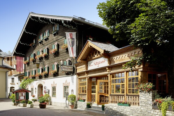Un bâtiment européen traditionnel, doté d’une façade en bois, de nombreuses fenêtres et de jardinières fleuries.