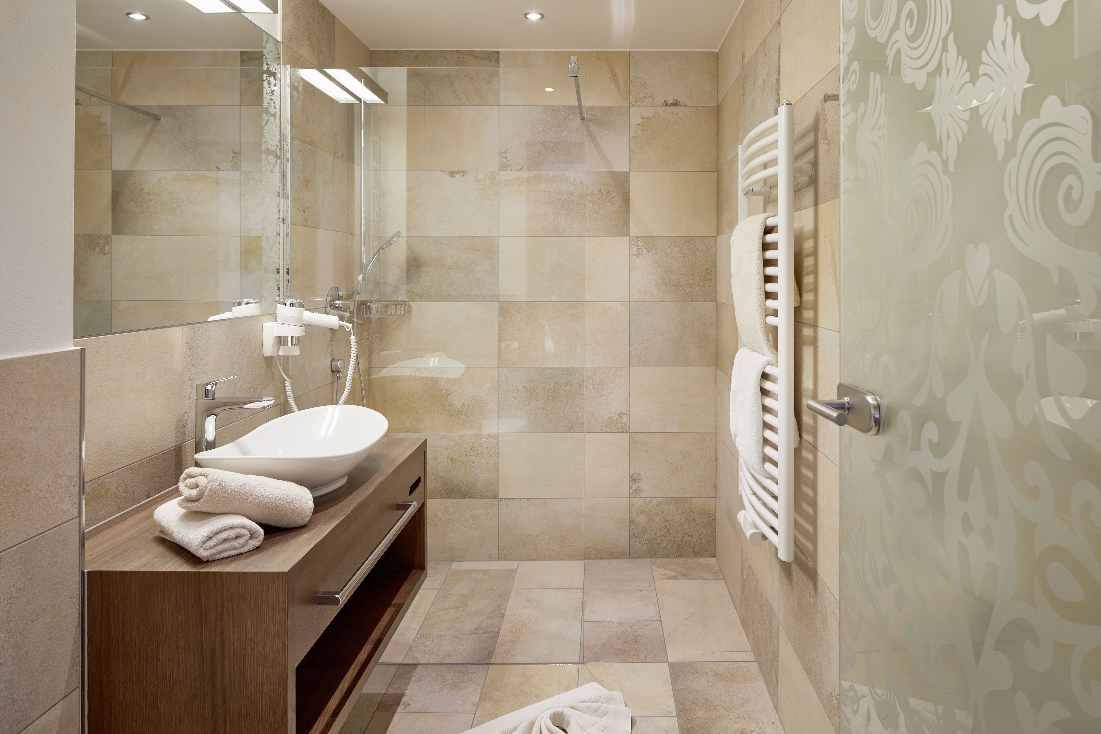 Un baño moderno con lavamanos, espejo y toallero.