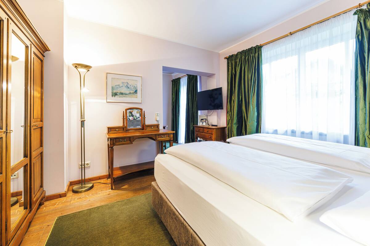 Une chambre d’hôtel avec un grand lit, un bureau avec une chaise, un téléviseur à écran plat et un tableau au mur.