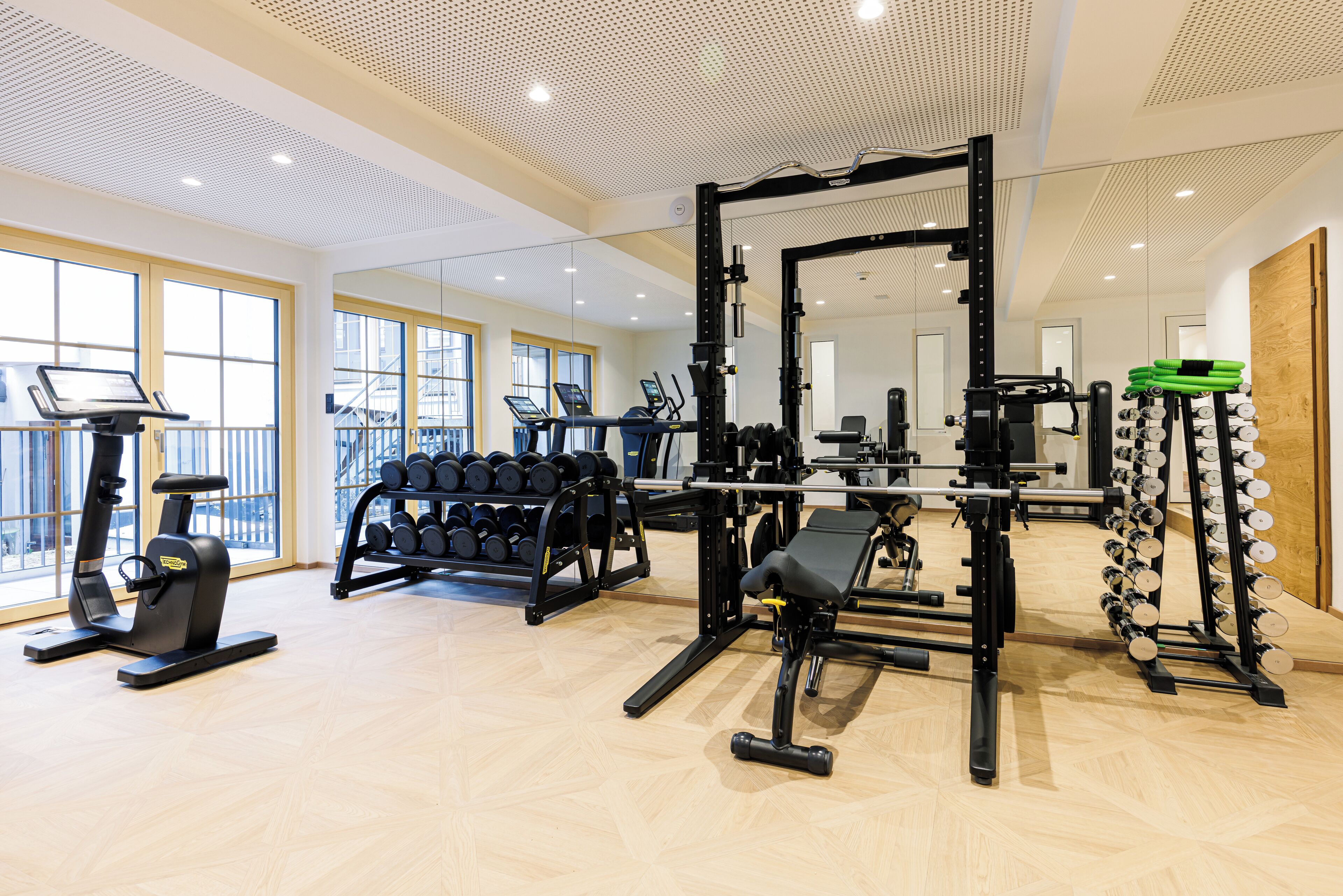 Un gimnasio con máquinas de cardio, equipo de levantamiento de pesas y mancuernas.