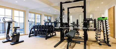 A gym with cardio machines, weightlifting equipment, and dumbbells.