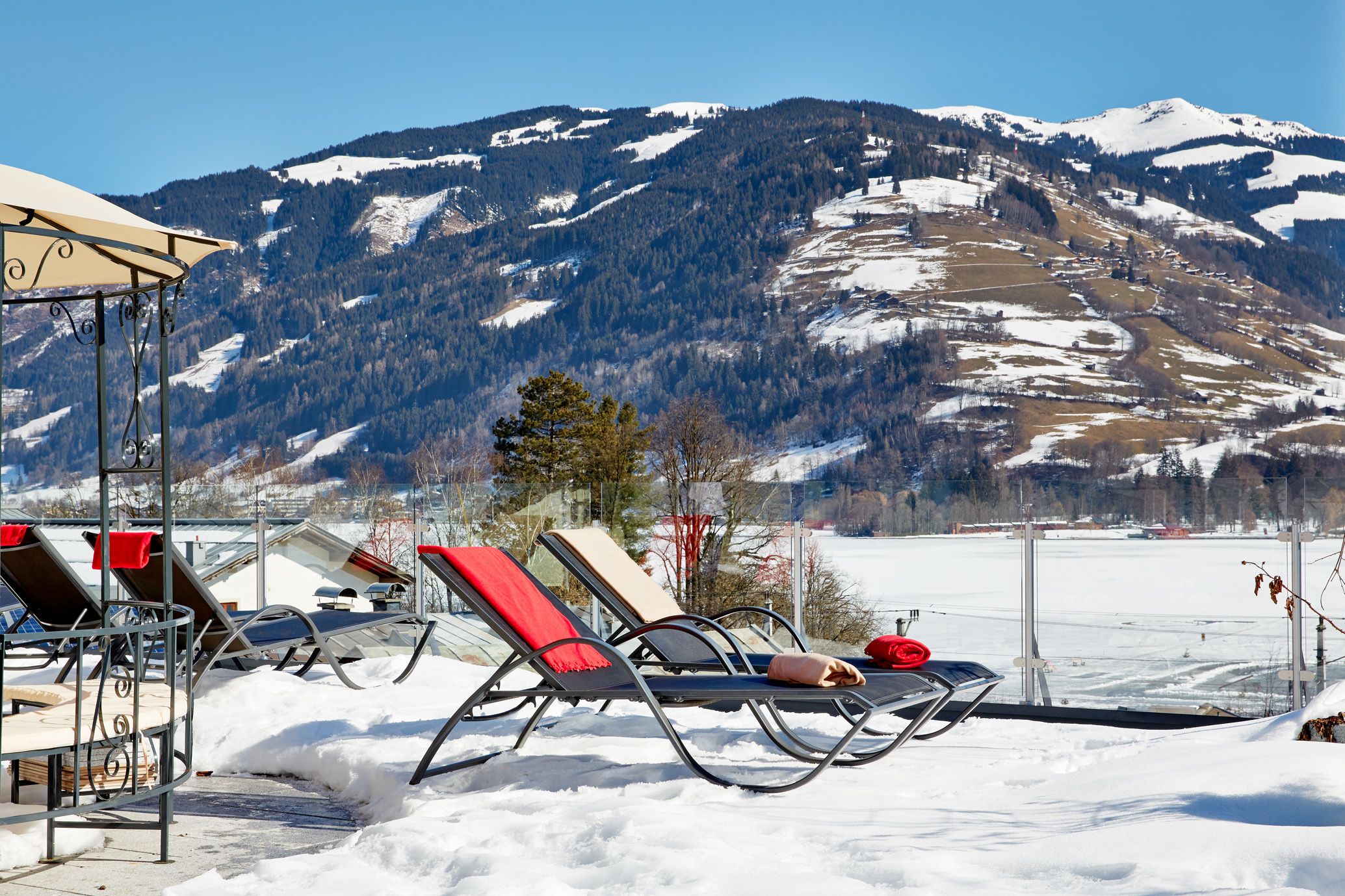 A snow-covered outdoor area with lounge chairs and a pergola.